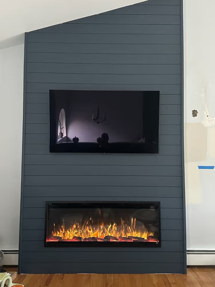Modern electric fireplace with a television mounted above it against a gray paneled wall.