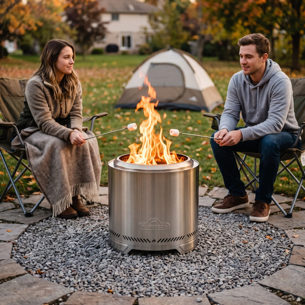 Napoleon Timberwolf 18-Inch Fire Pit in Stainless Steel on a gravel pad with a couple roasting marshmallows by a tent