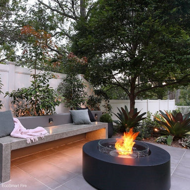 EcoSmart Fire Ark 39-Inch Round Concrete Black Fire Pit Table in a backyard