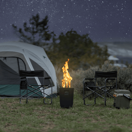 The Live Outdoor Firestorm Series I Portable Propane Fire Pit with the burner on under a star-filled sky at the campsite.