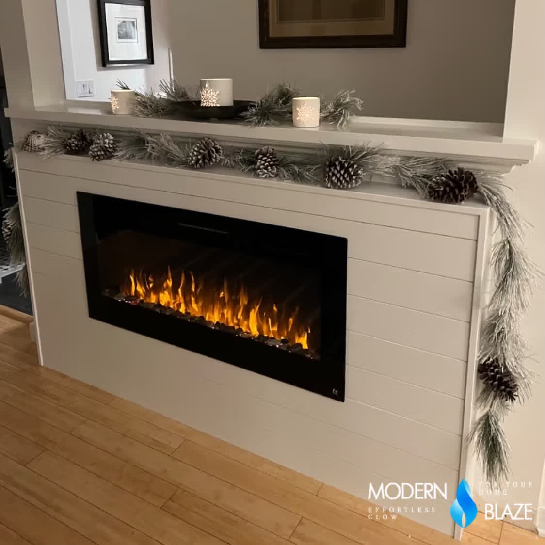 Touchstone Sideline 45 electric fireplace built into a white shiplap surround with a mantel, pine cone garland and candles, in a customer's home