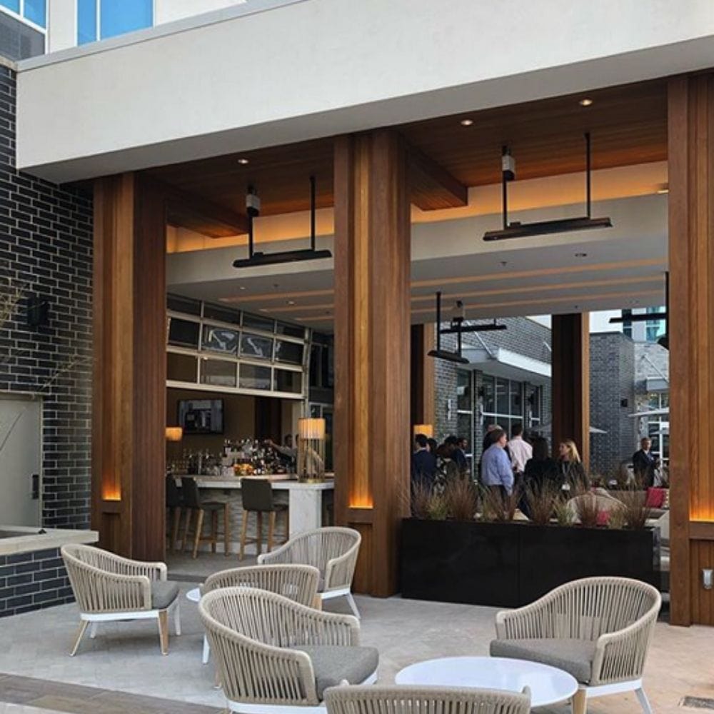 Black bromic tungsten electric patio heater mounted with suspension kit at a restaurant and bar