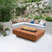 Top Fires Cabo Linear Corten Steel Gas Fire Pit Table in a lush cozy patio setting