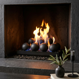 Majestic Contemporary vented gas burner with cannonballs, close-up of flames curling between the charcoal spheres in a modern stone fireplace