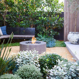 EcoSmart Fire Ark 39-Inch Round Concrete Gray Fire Pit Table in a lush patio setting