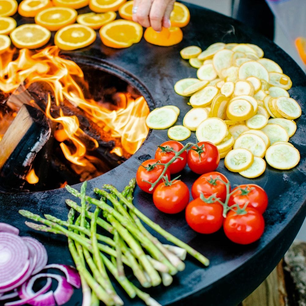 placing lemon, tomatoes, and vegetables on the seasons fire pits grill