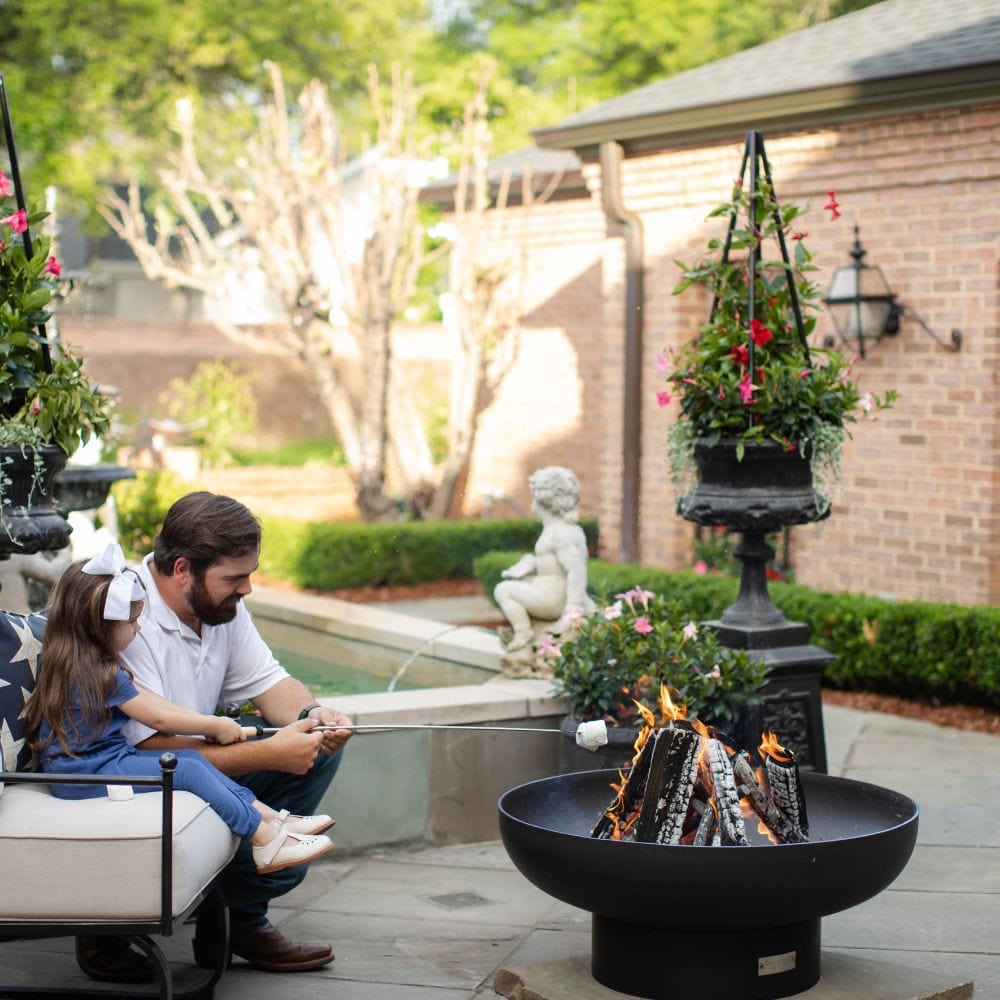 father and daughter roasting marshmallows on the seasons fire pits elliptical steel fire pit