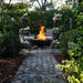 Seasons Fire Pits Vulcan Round Steel Fire Pit in a lush patio setting