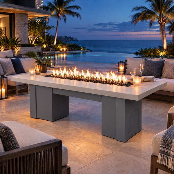 Top Fires Alameda 72-inch GFRC gas fire table with a Limestone tabletop and Gray base on a luxury poolside patio at blue hour