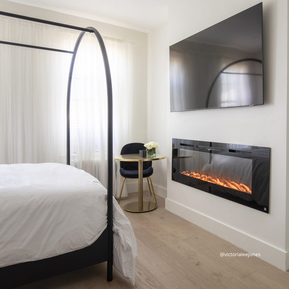 Touchstone Sideline 60 electric fireplace in a bedroom below a wall mounted TV