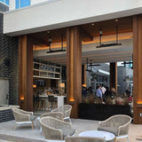 Black bromic tungsten electric patio heater mounted with suspension kit at a restaurant and bar