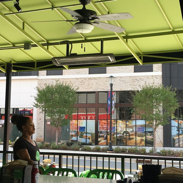Black bromic tungsten smart-heat electric patio heater mounted overhead at a cafe