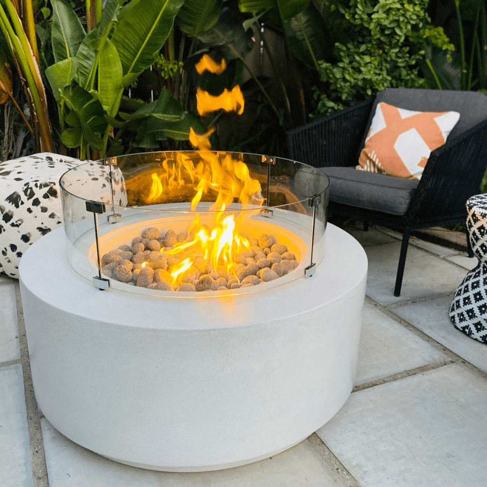 Modern Blaze Oblica Round Fire Pit in a lush cozy garden setting
