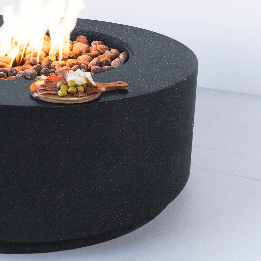 Modern Blaze Oblica Pacific Midnight Round Fire Pit with appetizers on the side