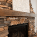 olde wood rough sawn wooden fireplace mantel on brick wall