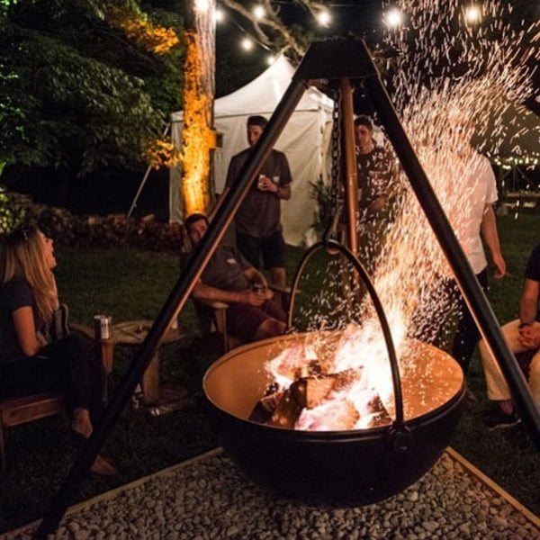 gathering around the cowboy cauldron fire pit grill at night
